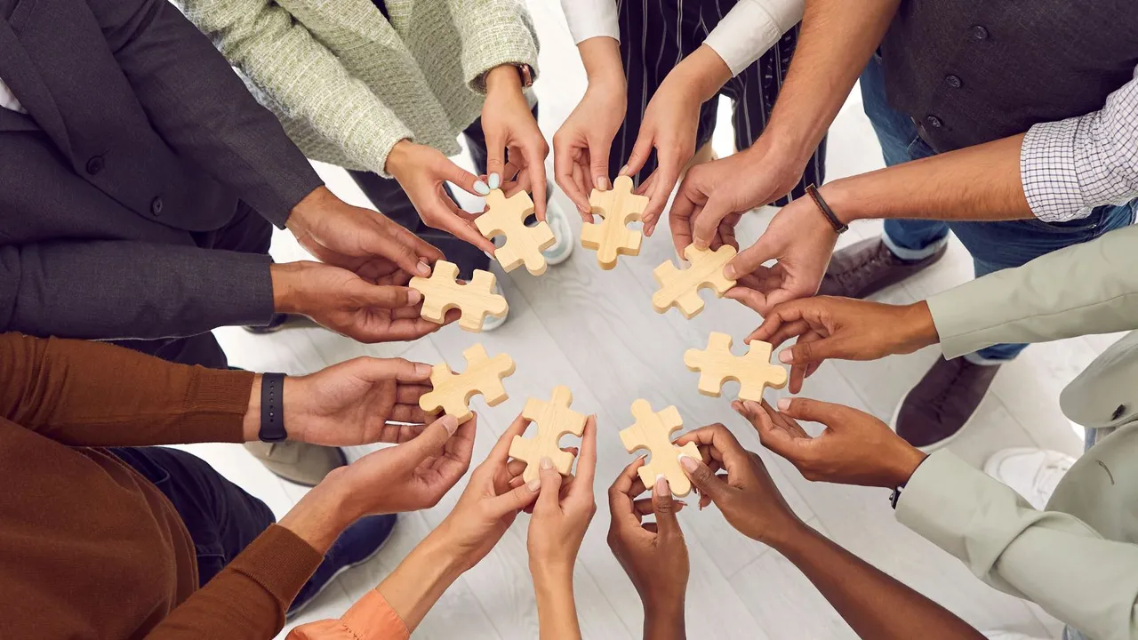 A group of people from different cultures standing in a circle holding puzzle pieces