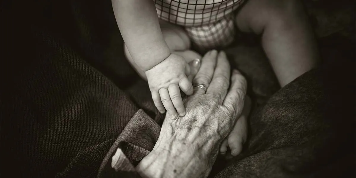 Close up of a baby and an older person holding hands