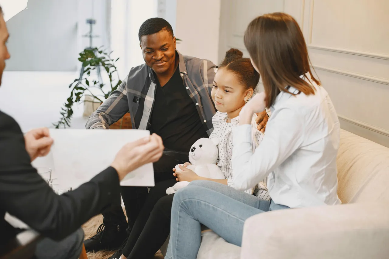 Family sitting on a couch looking comfortable. Therapist is sitting in front of them.