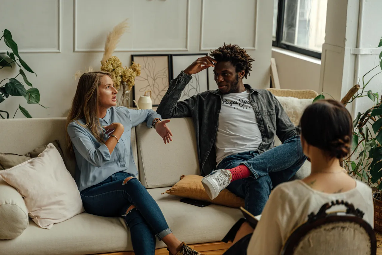 Couples sitting on a couch with the therapist on the foreground looking at them