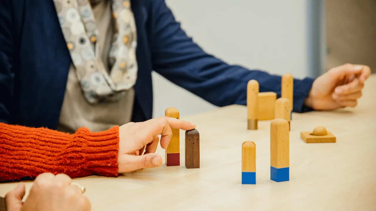 Client using wooden human figures in to visualize relationships